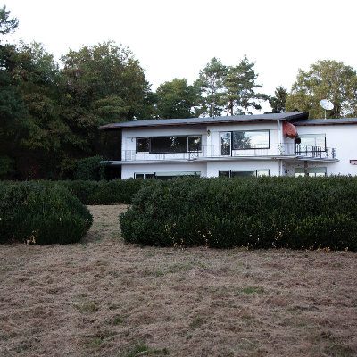Erbschaft Tierschutzverein Haus mit großen Fenstern, umgeben von einem gepflegten Garten und Bäumen.