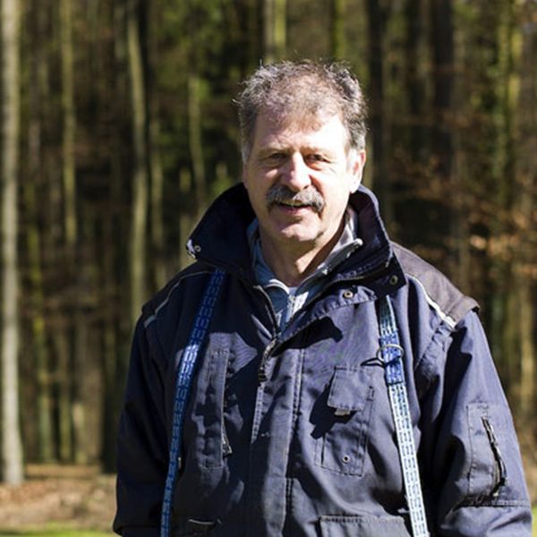 Gerd Schmidt Ein Mann mittleren Alters steht im Wald, trägt eine Jacke und schaut in die Kamera.